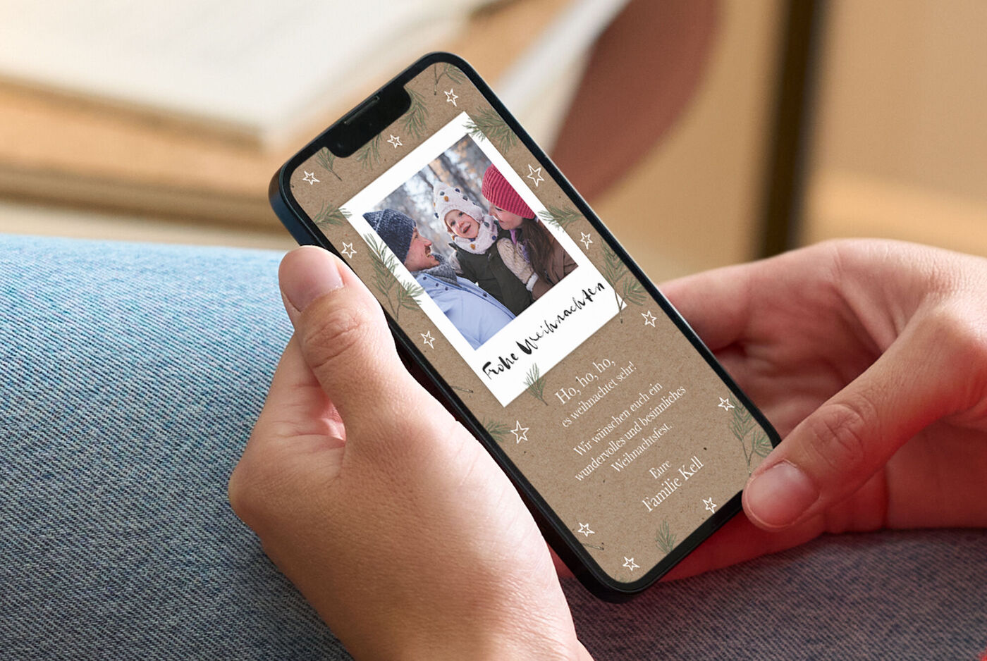 Person hält Smartphone mit liebevoll gestalteter digitalen CEWE Grußkarte zu Weihnachten