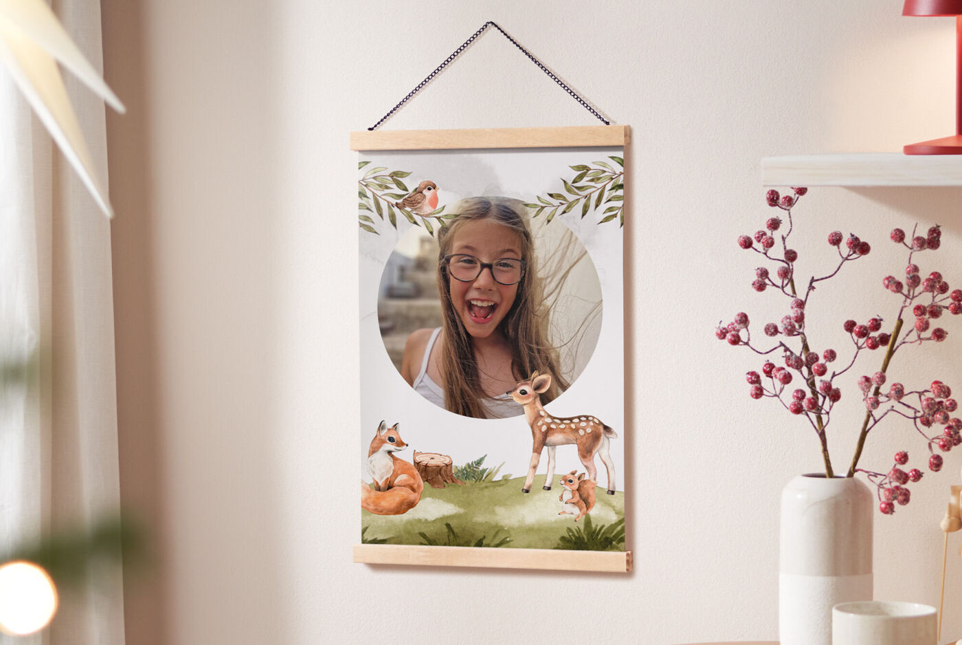 CEWE Poster mit Posterleiste mit Kinderfoto und Waldmotiven wie Reh, Fuchs, Vögeln und Pflanzen an einer Wand neben weihnachtlicher Dekorati