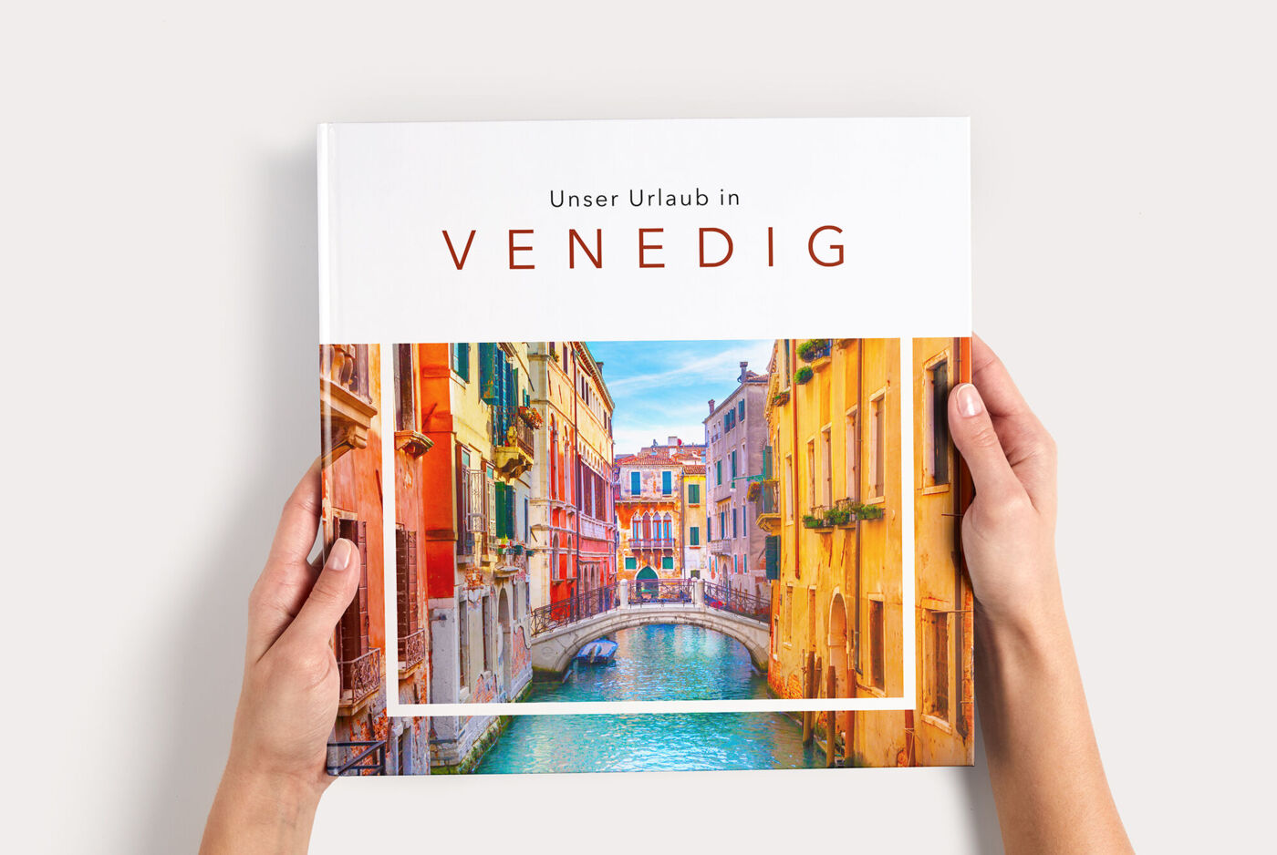CEWE FOTOBUCH XL mit dem Titel „Unser Urlaub in Venedig“ wird gehalten.