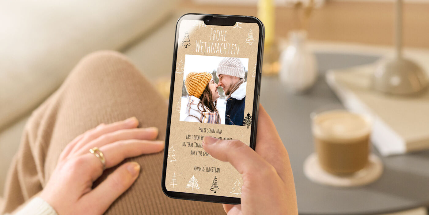 Eine Person hält ein Handy mit einer festlichen Grußkarte.