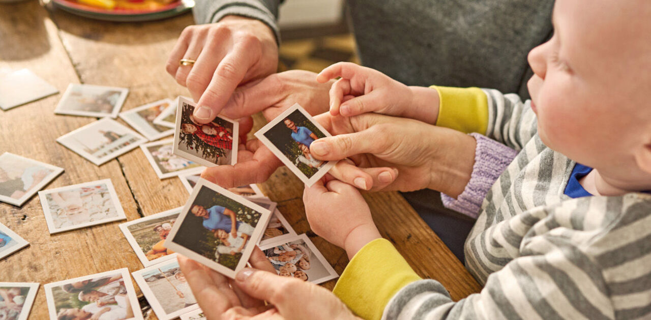 Kind spielt ein personalisiertes Foto-Memory mit einer erwachsenen Person.