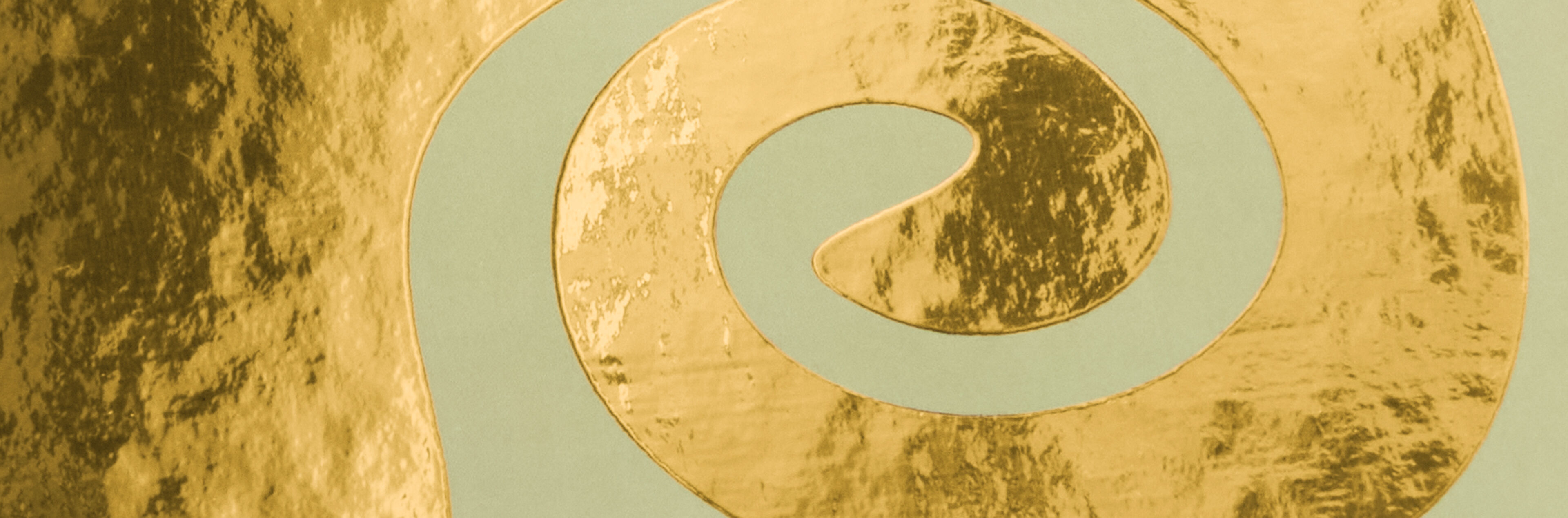 Spiralförmig geschwungene Goldveredelung auf mintgrünem Hintergrund.