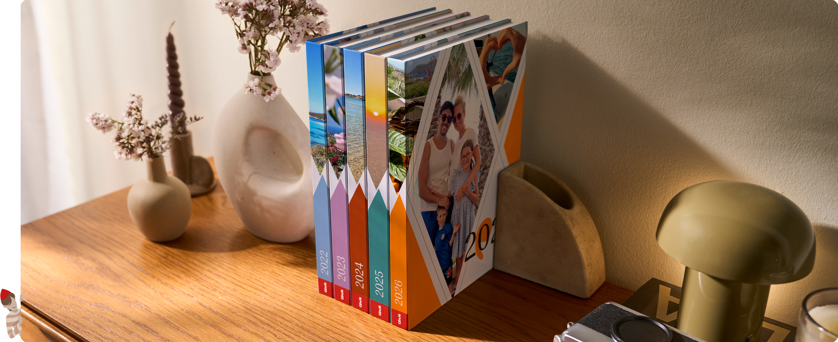 Mehrere bunte Bücher im einheitlichen Einband stehen aufrecht auf einem Holzregal neben dekorativen Vasen