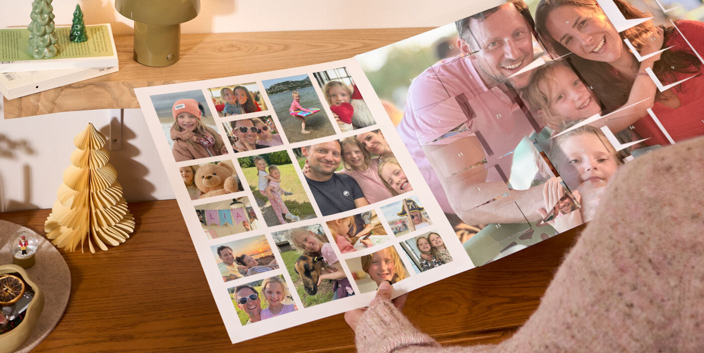 XXL Foto-Adventskalender mit Poster-Collage, bedruckt mit Familienfotos, steht auf einem Holzregal neben einer Lampe und Weihnachtsdeko