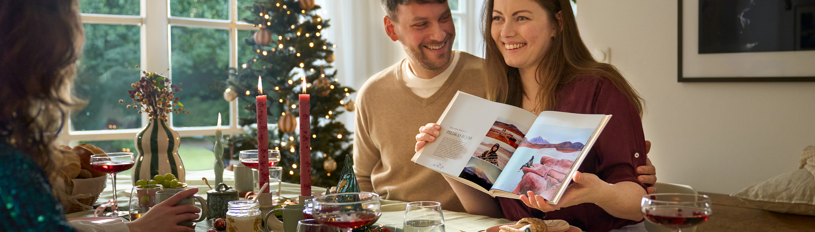 Gemeinsames Weihnachtsessen mit einem CEWE FOTOBUCH und fröhlichen Gesprächen.