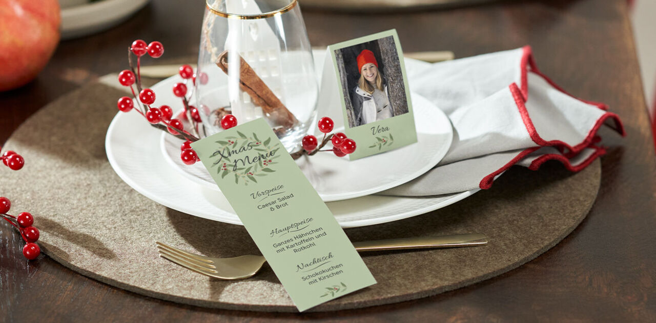 Festlich gedeckter Tisch mit Menükarte und Foto-Tischkarte mit weihnachtlichen Designs.