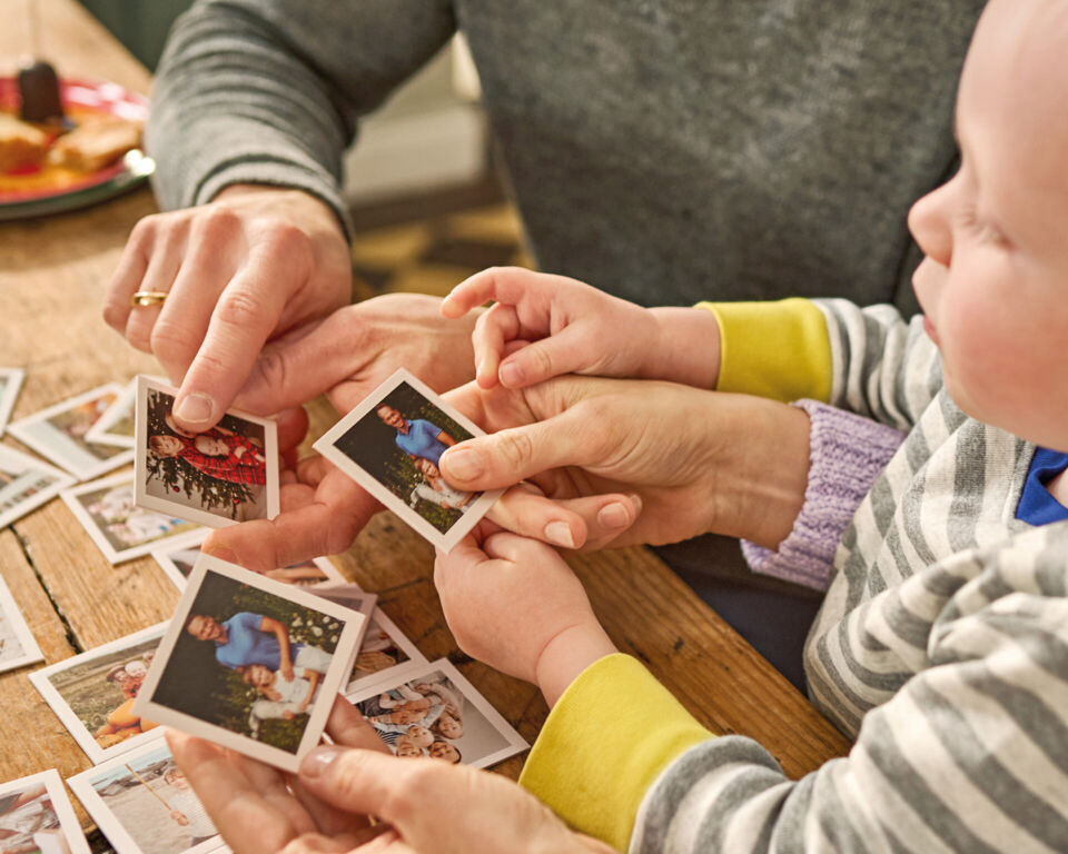 Kind spielt ein personalisiertes Foto-Memory mit einer erwachsenen Person.