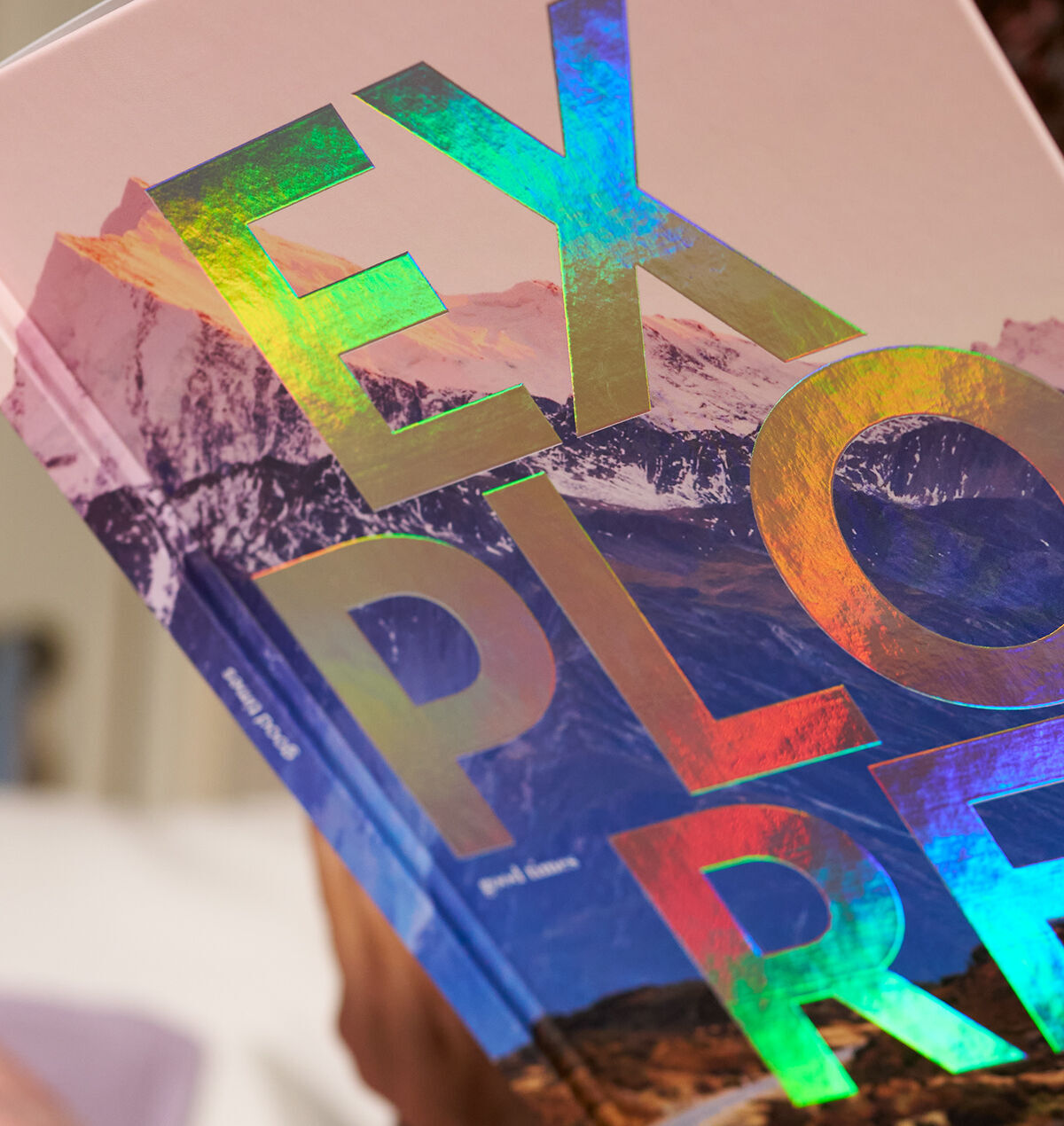 Eine Person hält ein CEWE FOTOBUCH mit einer holografischen Veredelung auf dem Cover.