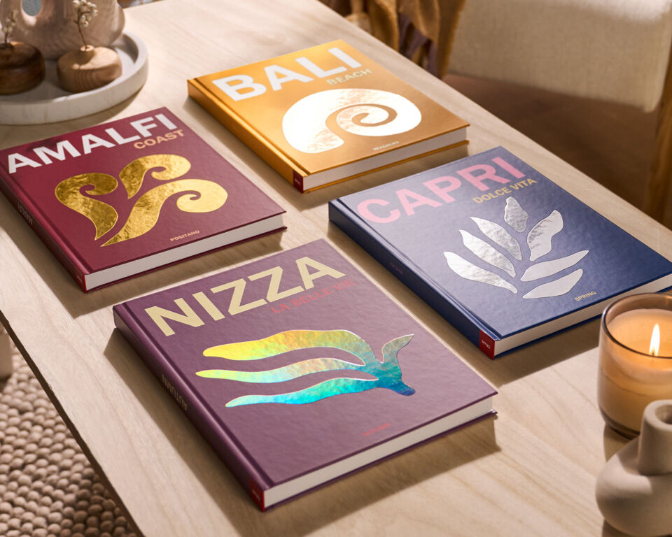 Verschiedene CEWE Fotobücher mit bunten Designs auf einem Tisch.