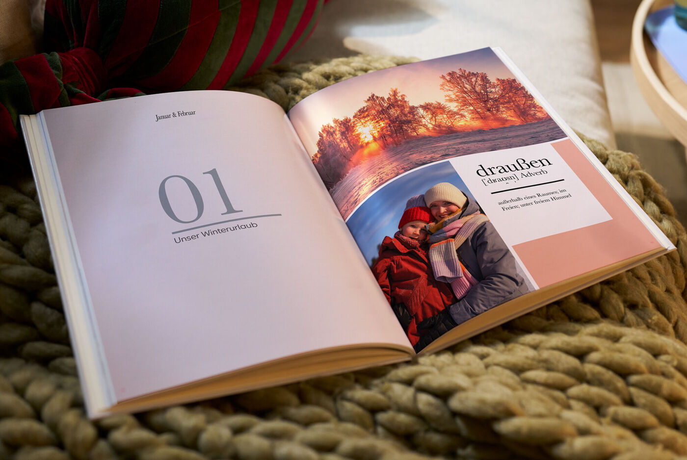 Fotobuch liegt aufgeschlagen auf einer Decke. Man sieht eine winterlich gestaltete Doppelseite.